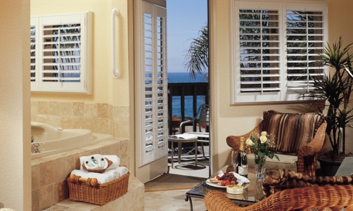 Plantation shutters on casement windows in a lakefront room.